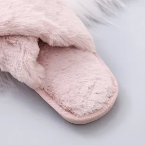 Close-up of pink fuzzy slippers showing soft plush texture and cross strap design.