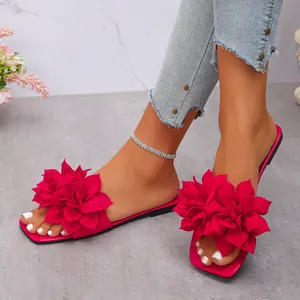 Stylish rose red flat sandals with 3D flower decor, shown on a model for beach fashion.