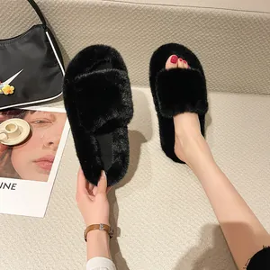 Detail view of stylish black fuzzy platform slippers worn on foot and held by hand