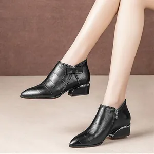Detailed macro view of women's black leather ankle boots with side zip and bow detail