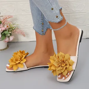 Close-up of women's beige flat slide sandals with large yellow flower and square toe