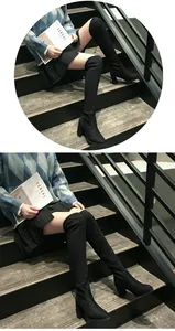 Détail de bottes cuissardes noires à talons hauts carrés portées par un mannequin