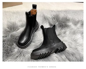 Detailed view of black platform Chelsea boots on a soft grey faux fur rug