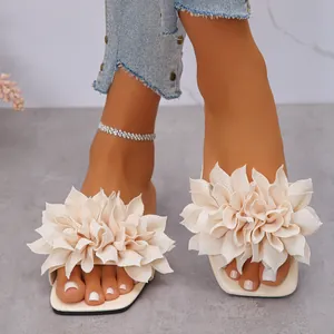 Close-up of women's flat sandals with elegant fabric flower and square toe