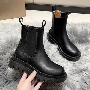 Close-up of black platform Chelsea boots featuring thick lug soles and matte finish