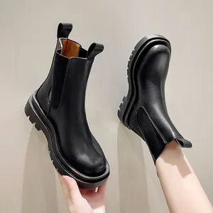 Macro view of black platform Chelsea boots showing thick sole and matte leather texture.