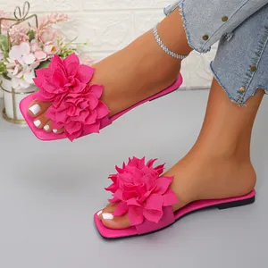 Close-up detail of fuchsia flat sandals featuring vibrant multi-layered floral decorations