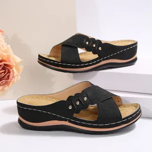 Détail de sandales compensées noires avec brides croisées et rivets dorés élégants