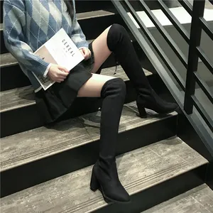 Gros plan d'une femme portant des bottes noires au-dessus du genou à talons hauts