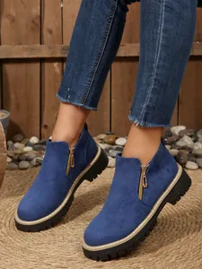 Detailed view of women's blue suede round-toe ankle boots featuring side gold-tone zippers