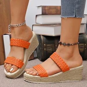 Detailweergave van de oranje geweven bandjes op sleehak sandalen met stroachtige zool.
