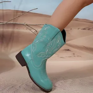 Turquoise western cowboy boot for women with white ethnic embroidery in desert setting