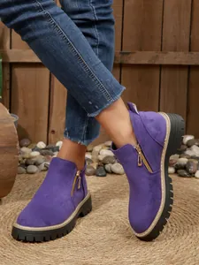 Purple suede-like platform ankle boots featuring side gold zippers and chunky lug soles.