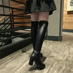 Bottes cuissardes extensibles à talons hauts noirs portées par un mannequin dans un décor intérieur