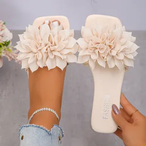 Detail view of cream flat slide sandals for women featuring large 3D fabric flowers