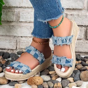 Detailweergave van blauwe denim sleehak sandalen met gerafelde bandjes en geweven zool
