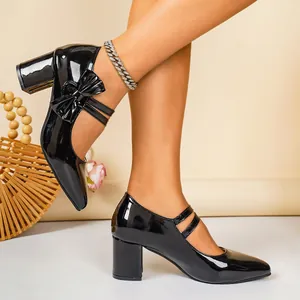 Close-up of black patent leather chunky heel Mary Jane shoes with bow detail
