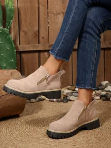 Side-view of beige suede ankle boots with zip detail and chunky lug sole.