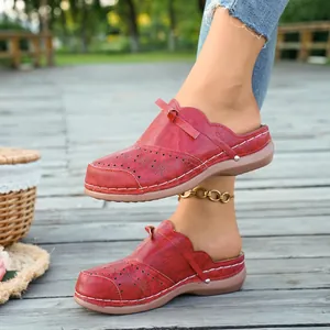 Primer plano de mules planos rojos para mujer con lazo y calados en terraza de madera