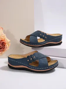 Détail des sandales compensées bleu marine avec design croisé élégant et rivets métalliques.