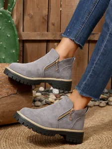 Close-up of women's grey faux suede ankle boots with side zipper and chunky sole.