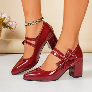 Detailed view of burgundy patent leather block heel shoes featuring an elegant bow detail
