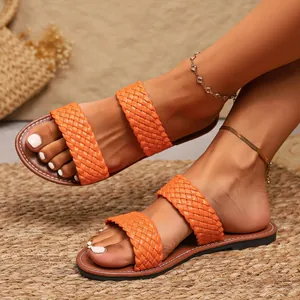 Detailweergave van stijlvolle helder oranje gevlochten platte sandalen met bandjes voor dames