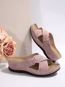 Détail de sandales compensées en daim mauve avec des brides croisées et des clous