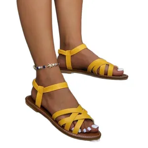 Stylish yellow flat Roman sandals with cross straps for women's summer beach wear.