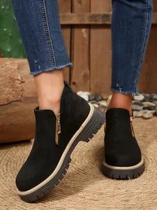 Detailed view of black suede ankle boots with side gold zipper and thick lug sole
