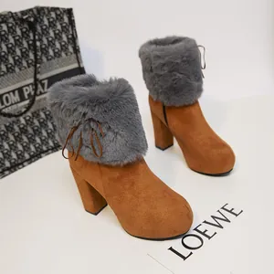 Detail of brown suede high-heeled ankle boots featuring grey faux fur trim and thick heels.