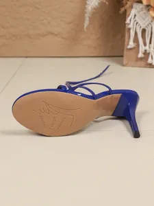 Gros plan d'un talon aiguille bleu et d'une semelle en caoutchouc avec motif gravé