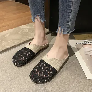 Primer plano de mules planos transpirables de encaje negro y lino beige para mujer.