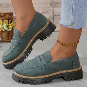 Détail de mocassins en daim bleu sarcelle rétro à semelle plateforme épaisse sur un modèle.