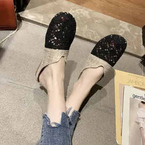 Primer plano de chinelas planas de mujer en encaje negro y lino beige en los pies
