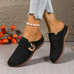 Elegant black closed-toe mules featuring a metallic heart buckle and decorative white stitching.