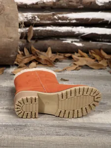 Detail view of orange winter boot showing slip-resistant sole and faux fur trim