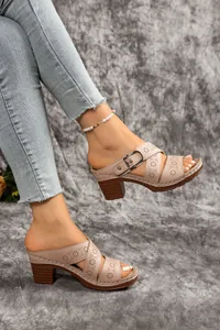 Detail of beige hollow-out chunky heel mule sandals with decorative buckle and floral pattern