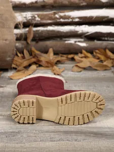 Detailed view of the anti-slip lug sole on burgundy fur-lined winter suede boots