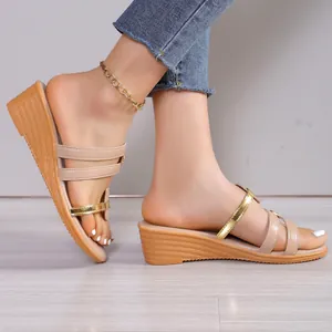 Dettaglio dei sandali con zeppa da donna in beige e oro con elegante design a più cinturini