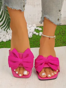 Detailed front view of women's pink flat slippers featuring large decorative bow accents for summer