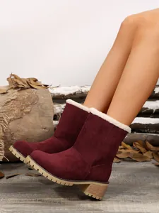 Close-up of burgundy suede winter boots featuring white faux fur lining and a sturdy mid-heel