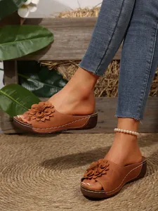 Detail of brown women's wedge sandals with 3D floral accent and white stitching details