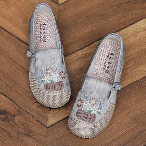 Detailed view of grey traditional Chinese embroidered shoes with floral patterns on wood.