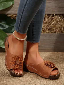 Detailed view of women's brown wedge sandals featuring a large 3D flower and white stitching.