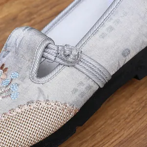 Detailed view of traditional Chinese embroidered shoes with intricate fabric patterns and buckle.