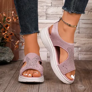 Nahaufnahme von rosa Strick-Sandalen mit Strasssteinen und einer weißen Plateausohle