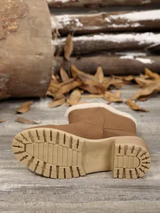Detailed view of the non-slip sole and faux fur lining of brown winter boots