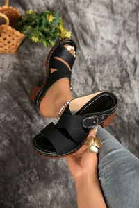 Close-up of black block heel sandals featuring intricate laser-cut patterns and a buckle