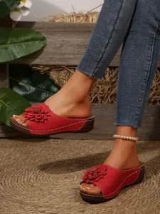 Detailed view of red women's wedge sandals featuring a large 3D flower and open toe design
